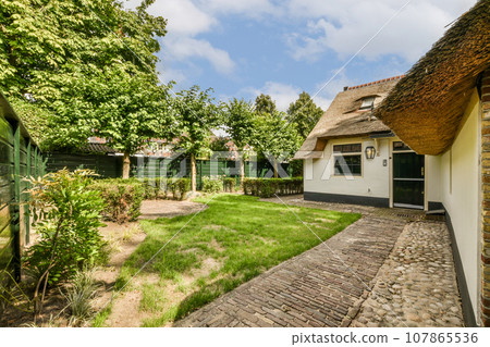 an outside area with some trees and buildings in the background, including a thatched roof on a white house an outside area with some trees and buildings in the background, including a thatched roof on a white house 107865536