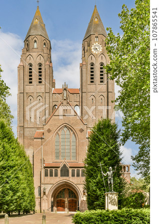 an old building with two towers on the top and one at the bottom, surrounded by green trees in front 107865541