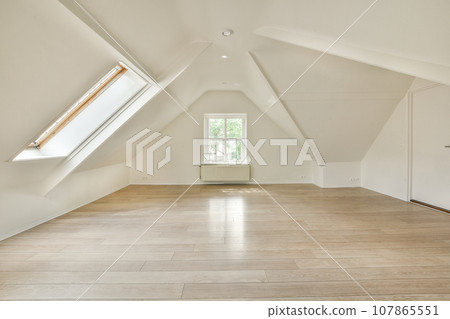 an empty room with wood floors and skylights in the corners on the right side of the room, there is a window an empty room with wood floors and skylights in the corners on the right side of the room, there is a window 107865551