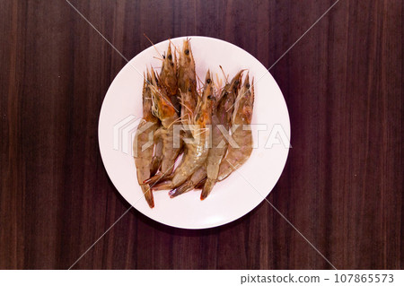 Raw shrimps on white plate. Raw shrimps on white plate. 107865573
