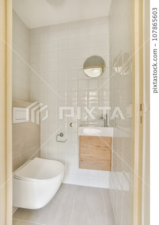 a small bathroom with white tiles and wood cabinet in the corner, as seen from the doorway leading to the toilet a small bathroom with white tiles and wood cabinet in the corner, as seen from the doorway leading to the toilet 107865603