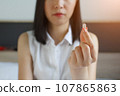 young woman taking pill,  taking drugs. Medicines at work 107865863