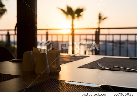 The rays of the sun at dawn fall on the table in a cafe with cutlery The rays of the sun at dawn fall on the table in a cafe with cutlery 107866033