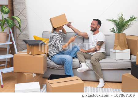 funny couple adds a dose of excitement to moving day, unpacking with laughter and snapping goofy selfies on their new home's sofa funny couple adds a dose of excitement to moving day, unpacking with laughter and snapping goofy selfies on their new home's sofa 107867109