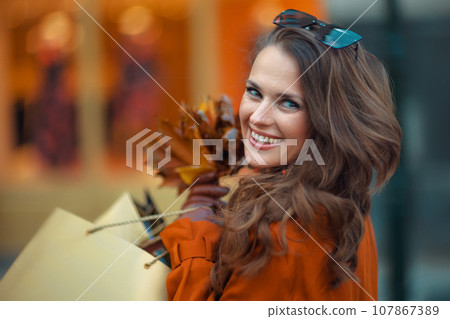 happy modern woman in orange trench coat 107867389