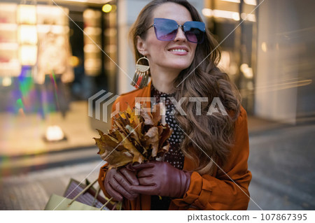happy modern 40 years old woman in orange trench coat 107867395