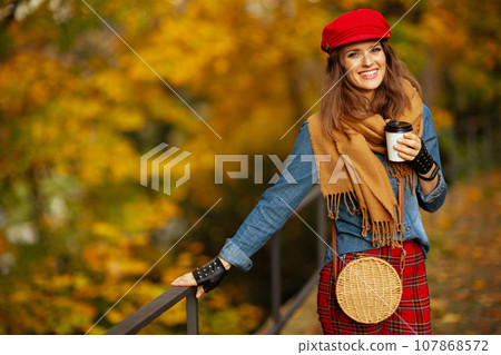 Portrait of happy modern woman in jeans shirt and red hat 107868572