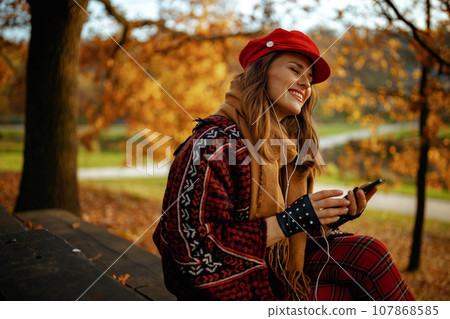 woman listening to music while sitting on bench in city park 107868585