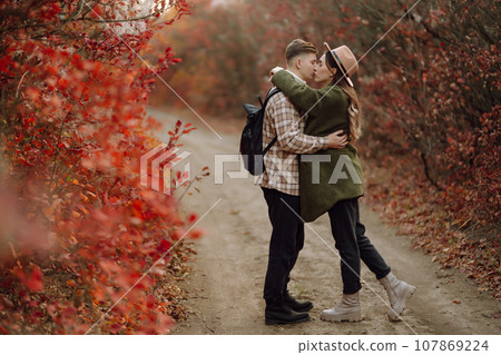 Happy couple in love newlyweds in casual clothes travel together, walk in autumn forest in nature. Happy couple in love newlyweds in casual clothes travel together, walk in autumn forest in nature. 107869224