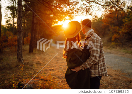 Young couple having fun walking on autumn park at sunset. Lifestyle, relaxation, vacations concept. Young couple having fun walking on autumn park at sunset. Lifestyle, relaxation, vacations concept. 107869225