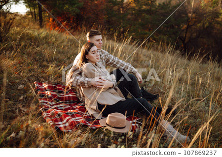 Happy couple in love newlyweds in casual clothes travel together, walk in autumn forest in nature. 107869237