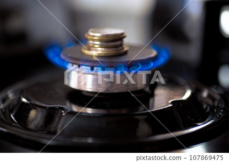 Coins accumulate on a burning gas burner. 107869475