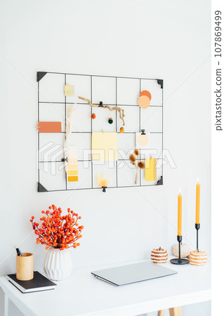 Home office desk with closed laptop, grid mood board with fall colors palette notes mockups and seasonal candles, flowers, pumpkins. Autumn inspiration and cozy mood. Hygge home fall decor. Vertical. 107869499