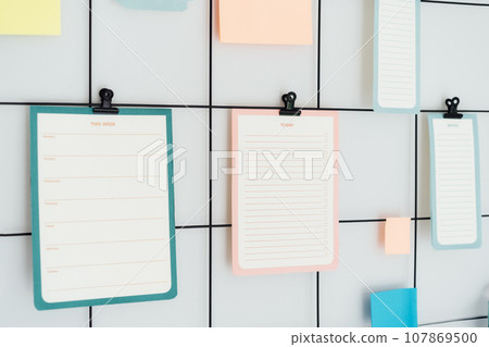 Close up grid mood inspiration board with mockup empty notes, Check lists and stickers on clamps for ideas, organizations, memories, wish lists with copy space. Plan for day and week. Selective focus 107869500