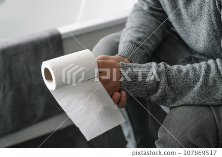 man with a paper roll in his hand sitting in the toilet 107869517