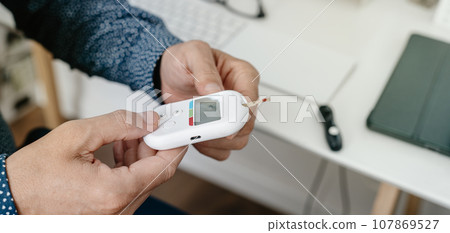 measures his blood glucose level in the office, banner measures his blood glucose level in the office, banner 107869527