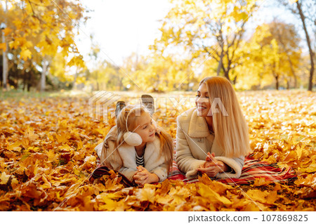 Portrait of happy mother and daughter in autumn forest at sunset. Autumn women. 107869825