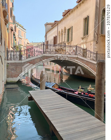 Canal with gondolas in Venice, Italy. Architecture and landmarks of Venice. Postcard with gondola. 107870129