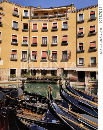 Canal with gondolas in Venice, Italy. Architecture and landmarks of Venice. Postcard with gondola. 107870154