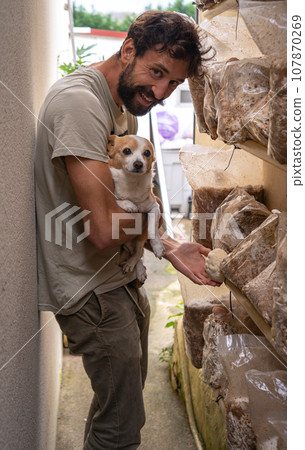 Young man posing with dog against mushroom farm 107870269