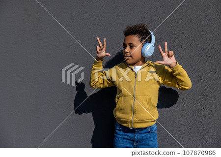 Boy in headphones dancing and looking excited Boy in headphones dancing and looking excited 107870986