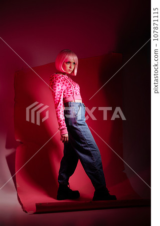 Woman model sitting on pink background at photo shoot in studio. 107871115