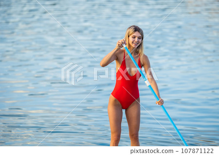 Girl with paddle on sub board floating on the water in the ocean. Girl with paddle on sub board floating on the water in the ocean. 107871122