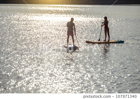 Happy couple man and woman floats on river on supboard. Happy couple man and woman floats on river on supboard. 107871340
