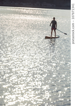 Man silhouette on the supboard on the middle of the lake. 107871341