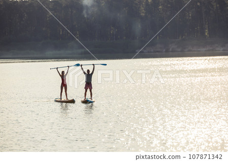 Happy couple man and woman floats on river on supboard. Happy couple man and woman floats on river on supboard. 107871342