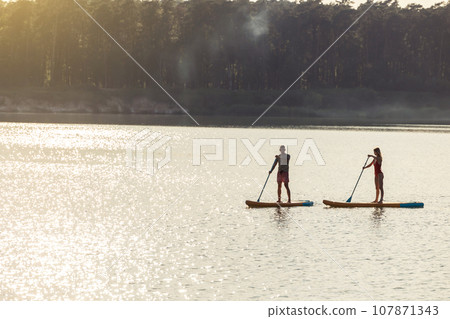 Happy couple man and woman floats on river on supboard. Happy couple man and woman floats on river on supboard. 107871343