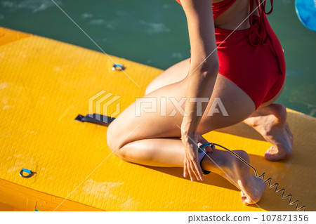 Unrecognizable attractive woman in swimwear on supboard. 107871356