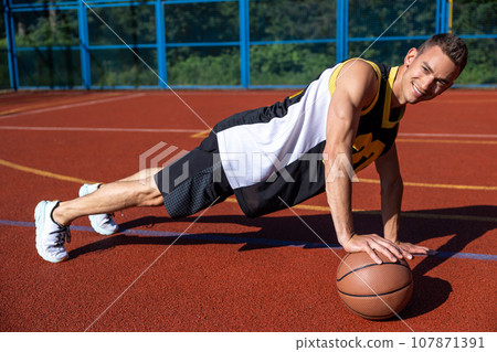 Athletic attractive man training on basketball court. 107871391
