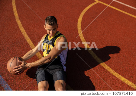 Athletic man doing sit ups and crunches exercising abdominal muscles outdoor on basketball court. Athletic man doing sit ups and crunches exercising abdominal muscles outdoor on basketball court. 107871410