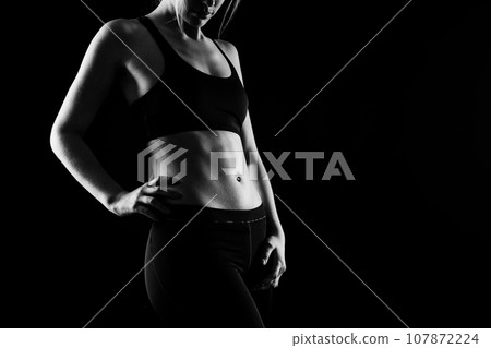 Beautiful young woman dressed in a sports uniform, posing in the studio. Healthy lifestyle, sport Beautiful young woman dressed in a sports uniform, posing in the studio. Healthy lifestyle, sport 107872224