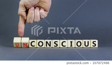 Conscious or unconscious symbol. Concept words Conscious Unconscious on wooden blocks. Beautiful grey table grey background. Psychologist hand. Psychology conscious or unconscious concept. Copy space. 107872486