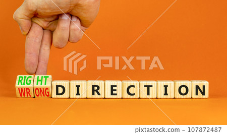 Right or wrong direction symbol. Concept words Right direction Wrong direction on wooden blocks. Beautiful orange background. Businessman hand. Business right or wrong direction concept. Copy space. Right or wrong direction symbol. Concept words Right direction Wrong direction on wooden blocks. Beautiful orange background. Businessman hand. Business right or wrong direction concept. Copy space. 107872487