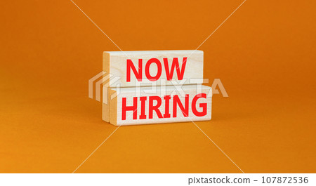 Now hiring symbol. Concept words Now hiring on beautiful wooden block. Beautiful orange table orange background. Business marketing, motivational now hiring concept. Copy space. 107872536