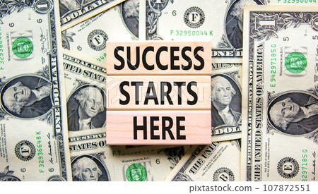 Success starts here symbol. Concept word Success starts here on beautiful wooden block. Dollar bills. Beautiful dollar bills background. Business motivational success starts here concept. Copy space. Success starts here symbol. Concept word Success starts here on beautiful wooden block. Dollar bills. Beautiful dollar bills background. Business motivational success starts here concept. Copy space. 107872551