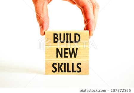 Build new skills symbol. Concept word Build new skills on beautiful wooden block. Businessman hand. Beautiful white table white background. Business, education build new skills concept. Copy space. 107872556