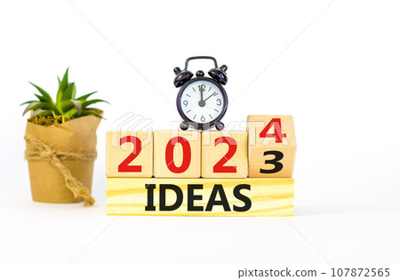 2024 ideas new year symbol. Businessman turns a wooden cube and changes words Ideas 2023 to Ideas 2024. Beautiful white background, copy space. Business 2024 ideas new year concept. 107872565