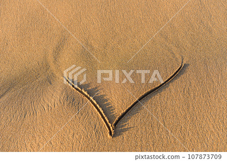 Heart shape drawn in the sand on a beach Heart shape drawn in the sand on a beach 107873709