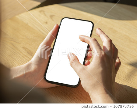 Hand holding mobile phone screen mockup, enlarging photo on blank display 107873756