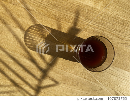 Cold brew coffee, iced cool fresh drink on wooden table on sunny day, top view 107873763