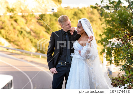 Happy newlyweds hugging against the backdrop of a beautiful mountain landscape 107874488