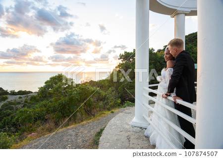 Newlyweds in a gazebo with columns on the seashore 107874507