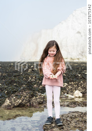 Little girl between Seaford and Eastbourne, East Sussex. Beach and sea in foggy morning 107875342