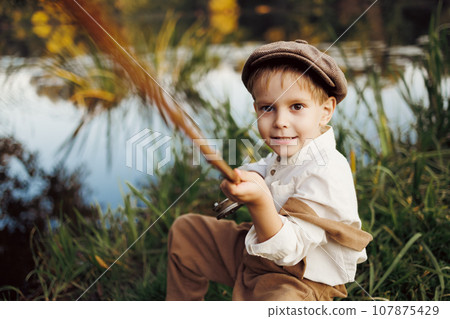 Child fishing at autumn lake 107875429