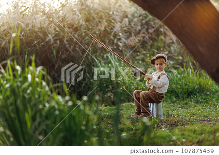 Little boy fishing at sunset Little boy fishing at sunset 107875439