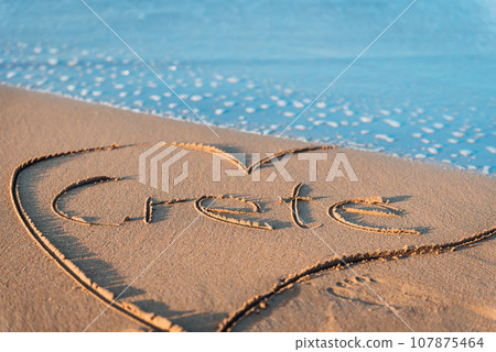 Heart on yellow sand and blue seawater 107875464